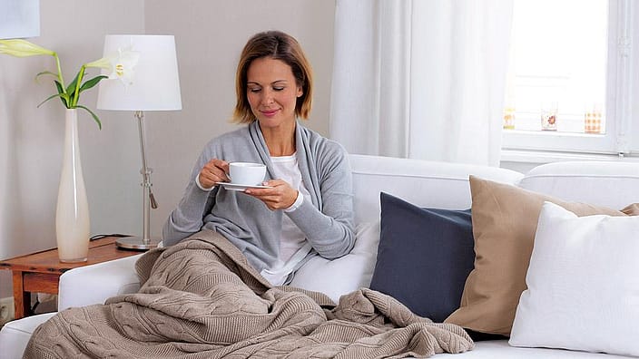 femme qui boit du thé dans son canapé
